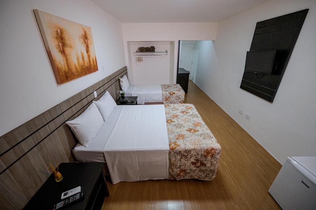 Une chambre d’hôtel avec un lit, une petite table, un téléviseur et un tableau au mur.