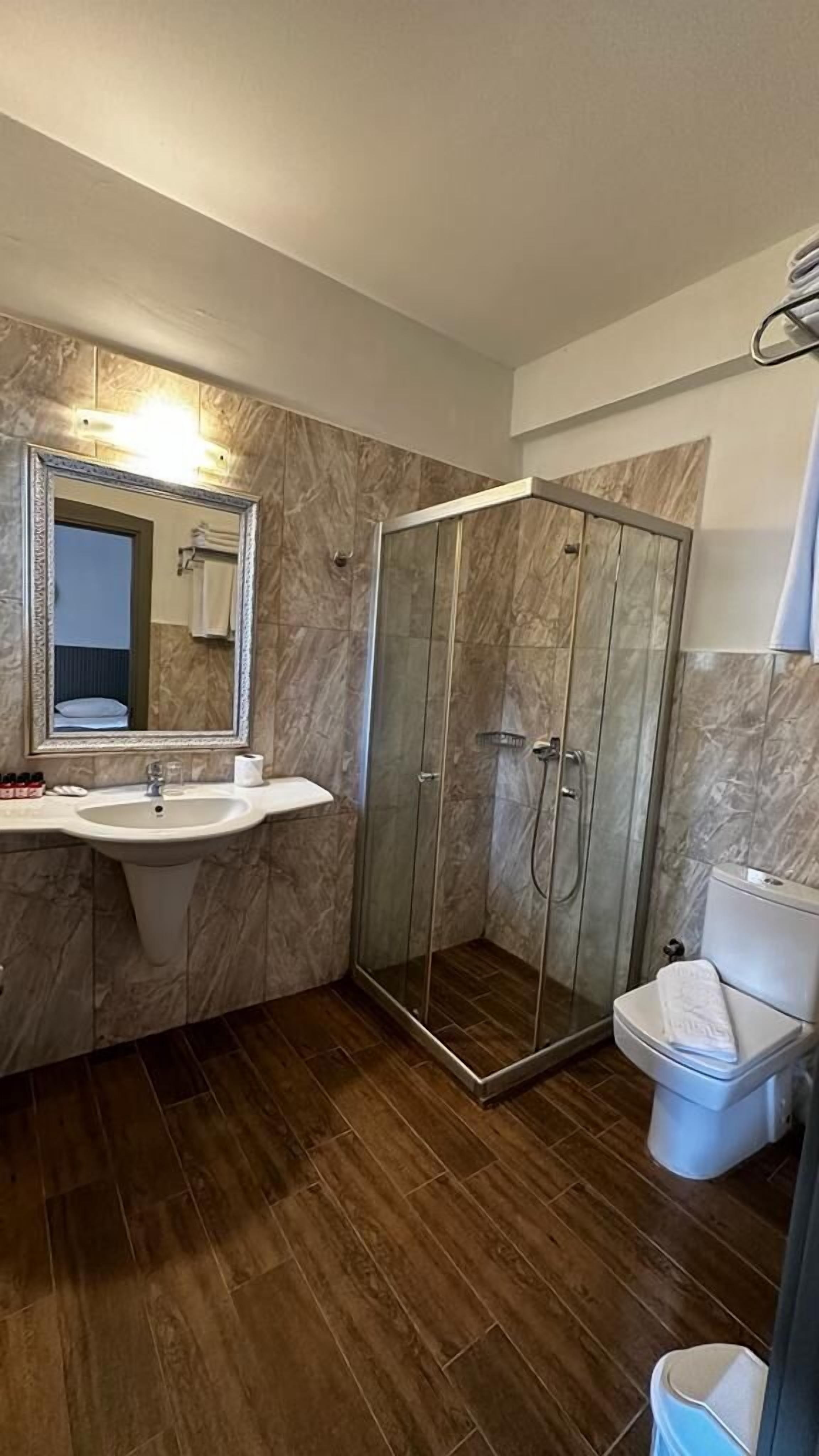 Un bagno con un mobile lavabo in marmo, una cabina doccia in vetro e un WC.