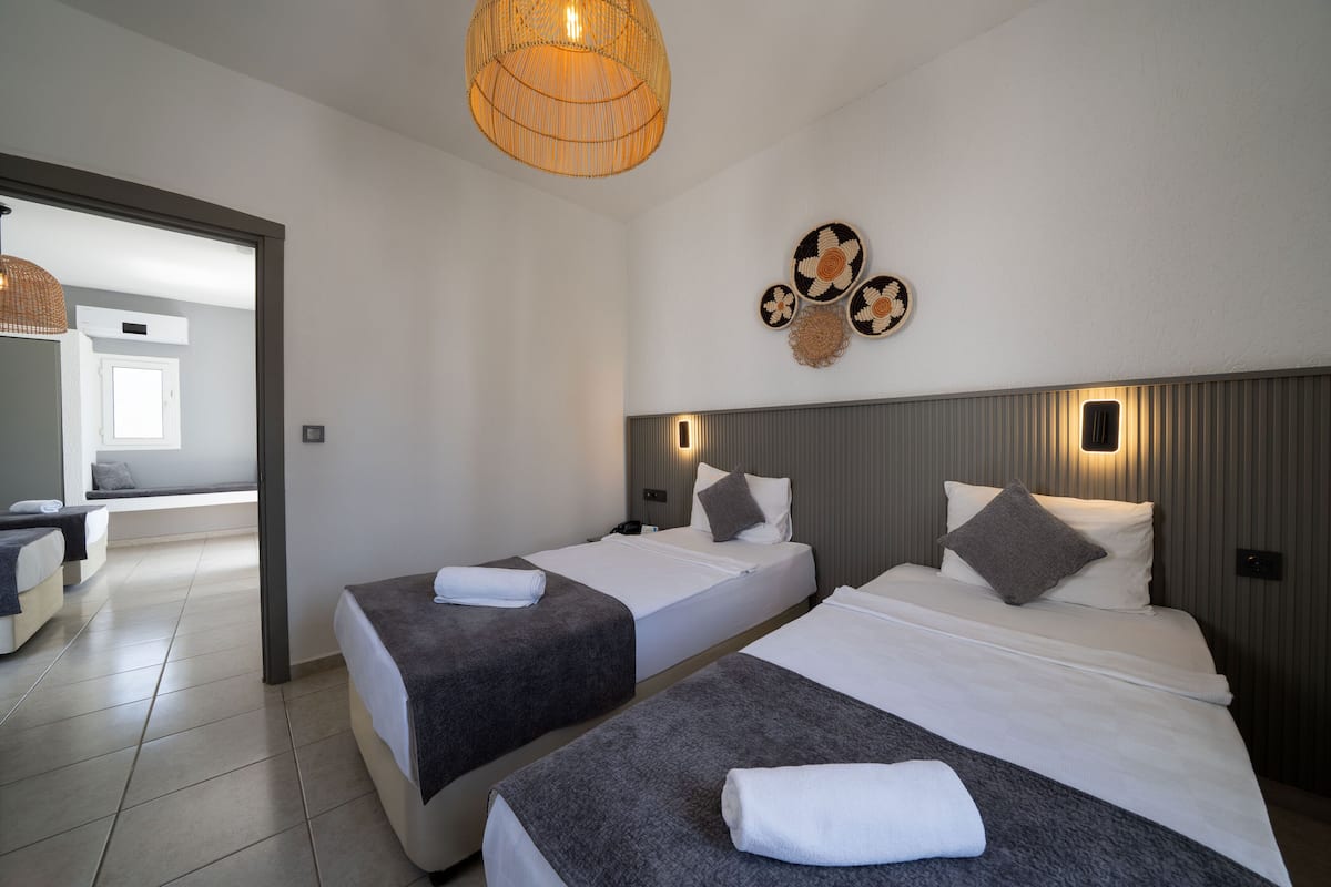 A hotel room with two beds, a large window, and a wall-mounted light fixture.