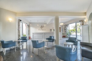 Un hall de hotel con asientos azules, una chimenea central y vistas al exterior.