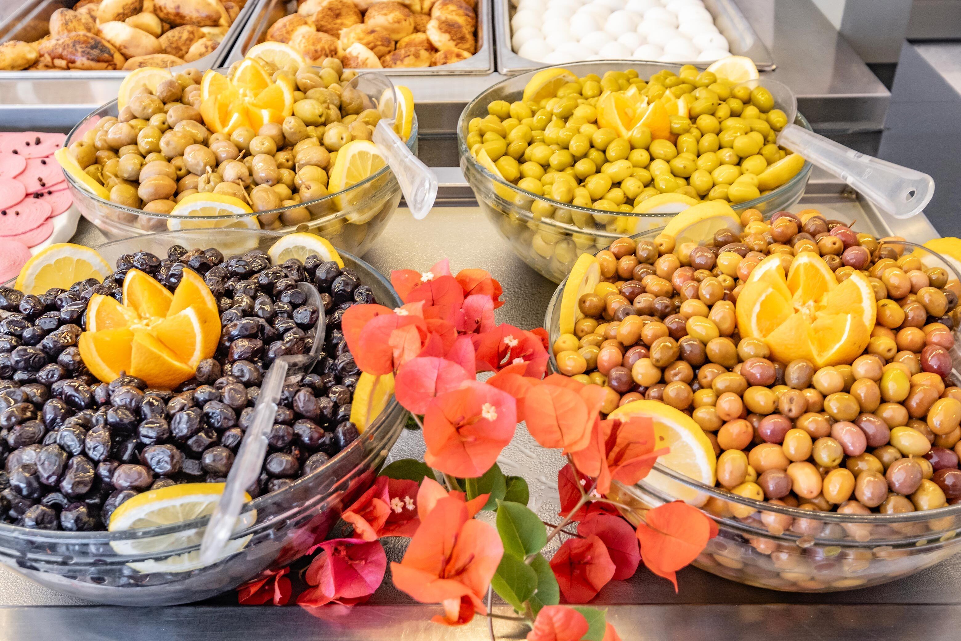 A buffet with various food options including olives, fruits, and other snacks.