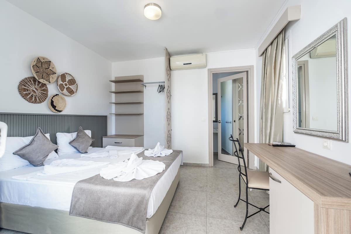 A modern hotel room with a neatly made bed, a desk with a mirror, and decorative wall art.