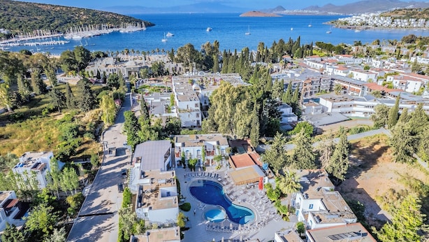 An aerial view of a coastal resort with a central swimming pool, villas, and a marina. - Paloma Family Club  (Bodrum)