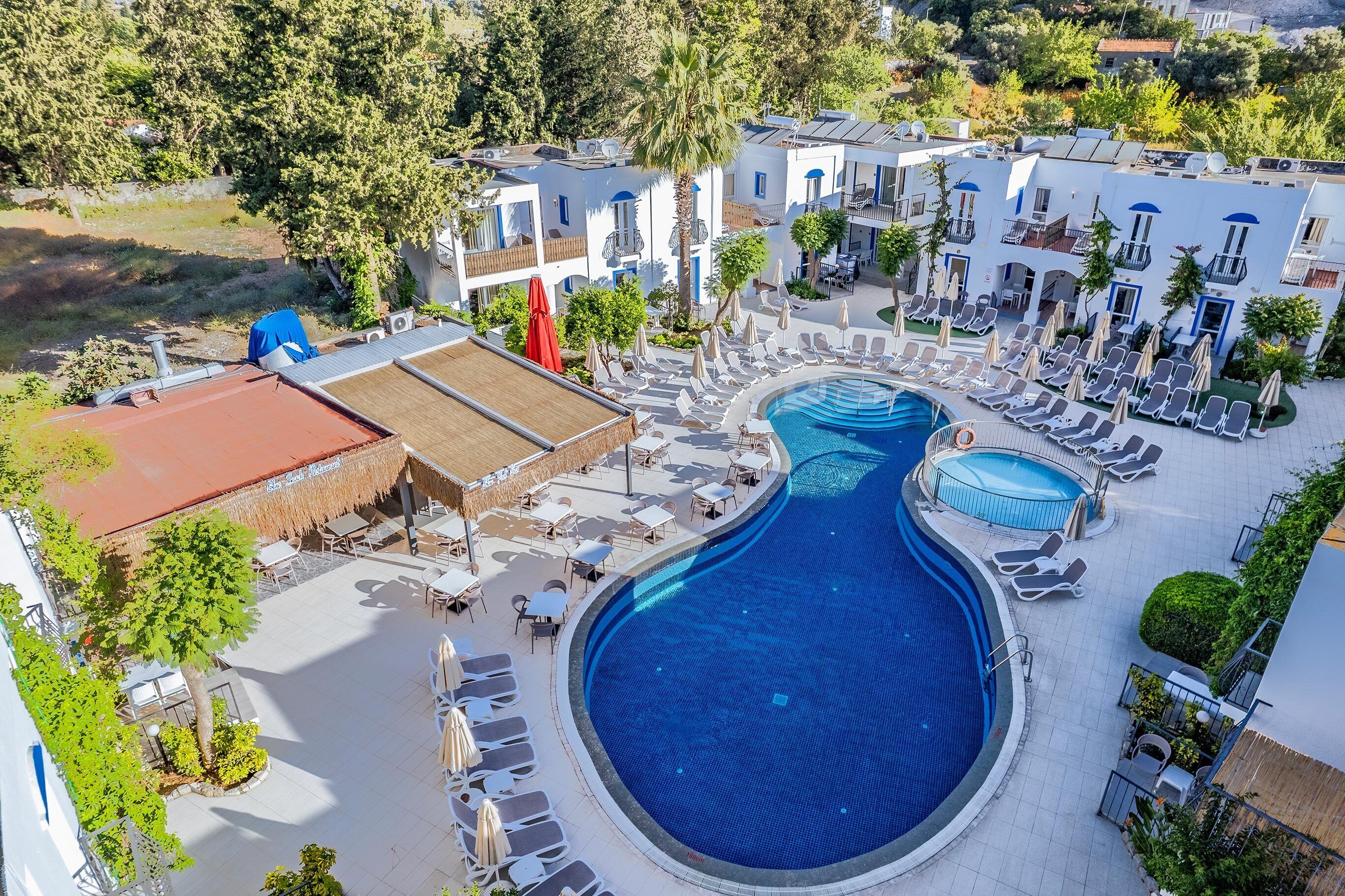 A resort with a large swimming pool, sun loungers, and a covered outdoor area.