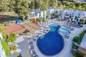 Un resort con una amplia piscina, tumbonas y un área exterior cubierta.