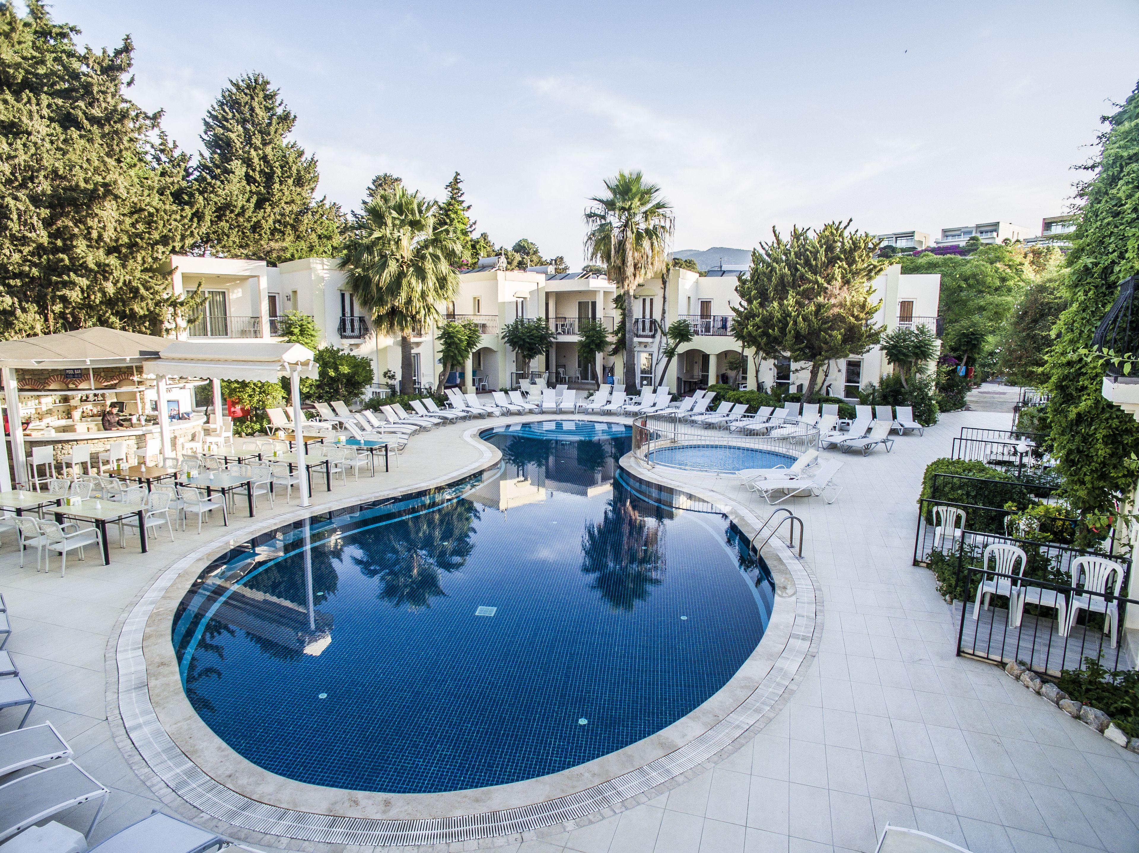 A resort pool area with multiple lounge chairs and a bar.