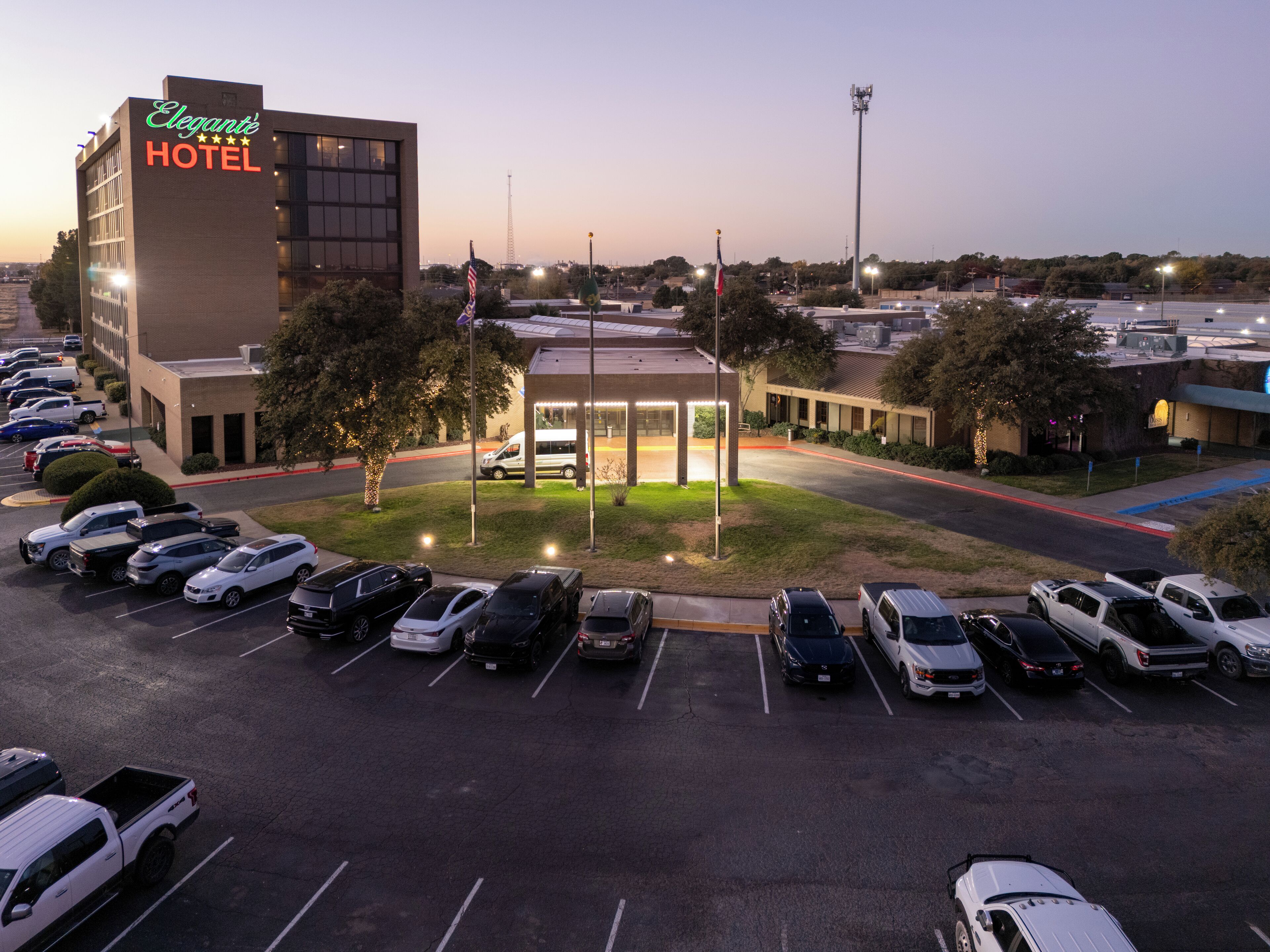 A hotel with a parking lot and a building with a sign that reads "Elegante Hotel".