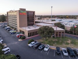 Vista aérea del Elegante Hotel, con estacionamiento, un edificio grande y paisaje circundante.