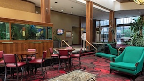 A lobby with a large aquarium, red and green seating, and a red carpeted floor. - MCM Elegante Hotel and Conference Center Odessa (Odessa)