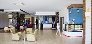 A spacious lobby with a reception desk, seating area, and a glass display case with pastries.