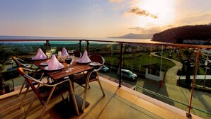 A dining area with a table set for four, overlooking a scenic view of a coastal landscape with mountains in the distance. - Ulu Resort Hotel - All Inclusive (Gülnar)