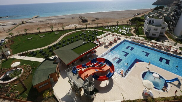 A resort with a large swimming pool, a water slide, and a beach view. - Ulu Resort Hotel - All Inclusive (Gülnar)