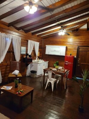 Un interior de madera con comedor, cocina y ventilador de techo.