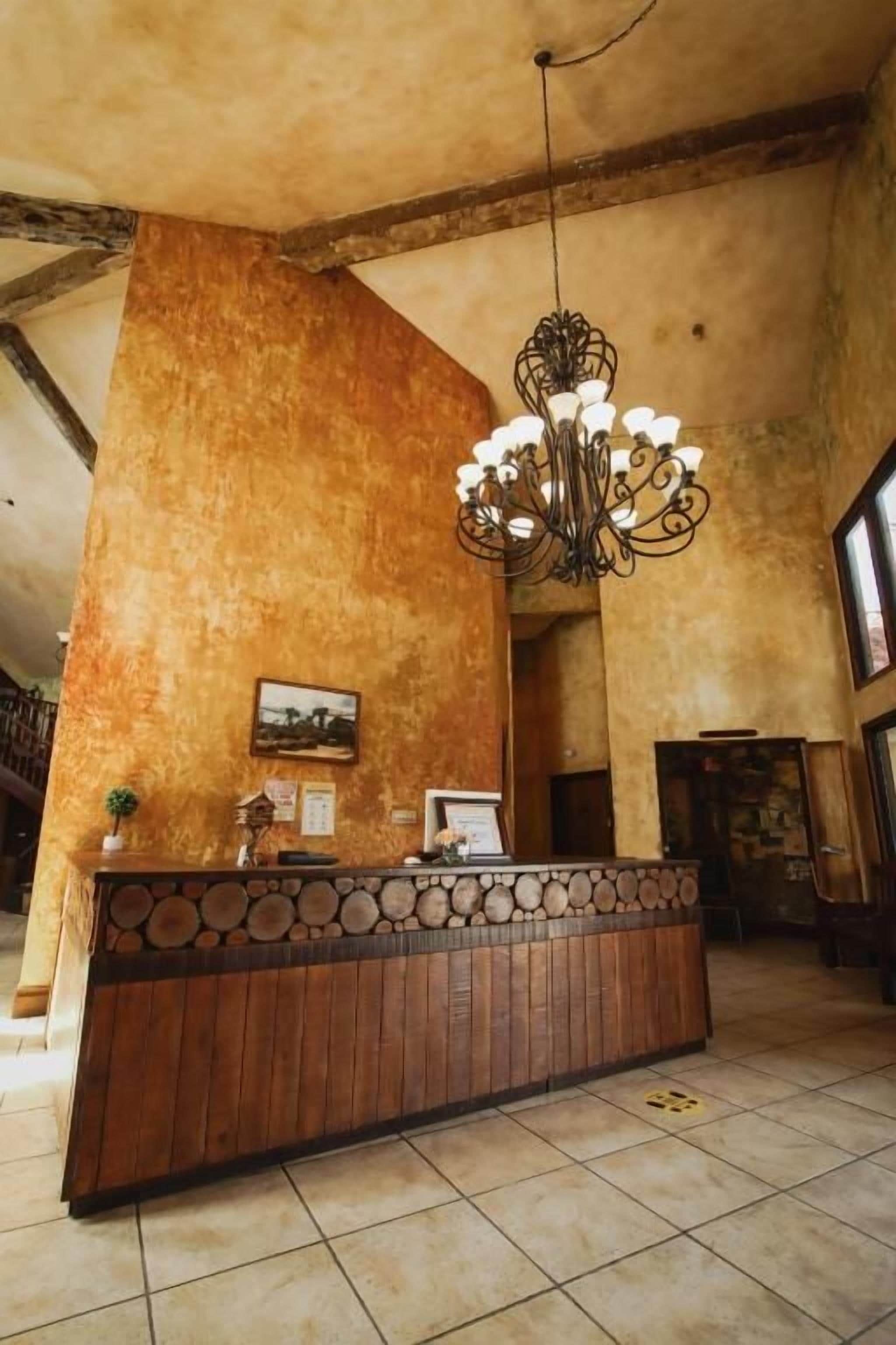 A reception area with a wooden reception desk, a chandelier, and a large window.