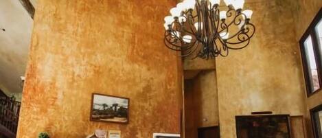 A reception area with a wooden reception desk, a chandelier, and a large window.