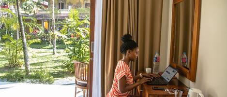 A room with a laptop, a water bottle, and a coffee maker on a wooden table.
