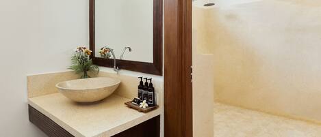 A bathroom with a large mirror, a bowl sink, and a shower area.