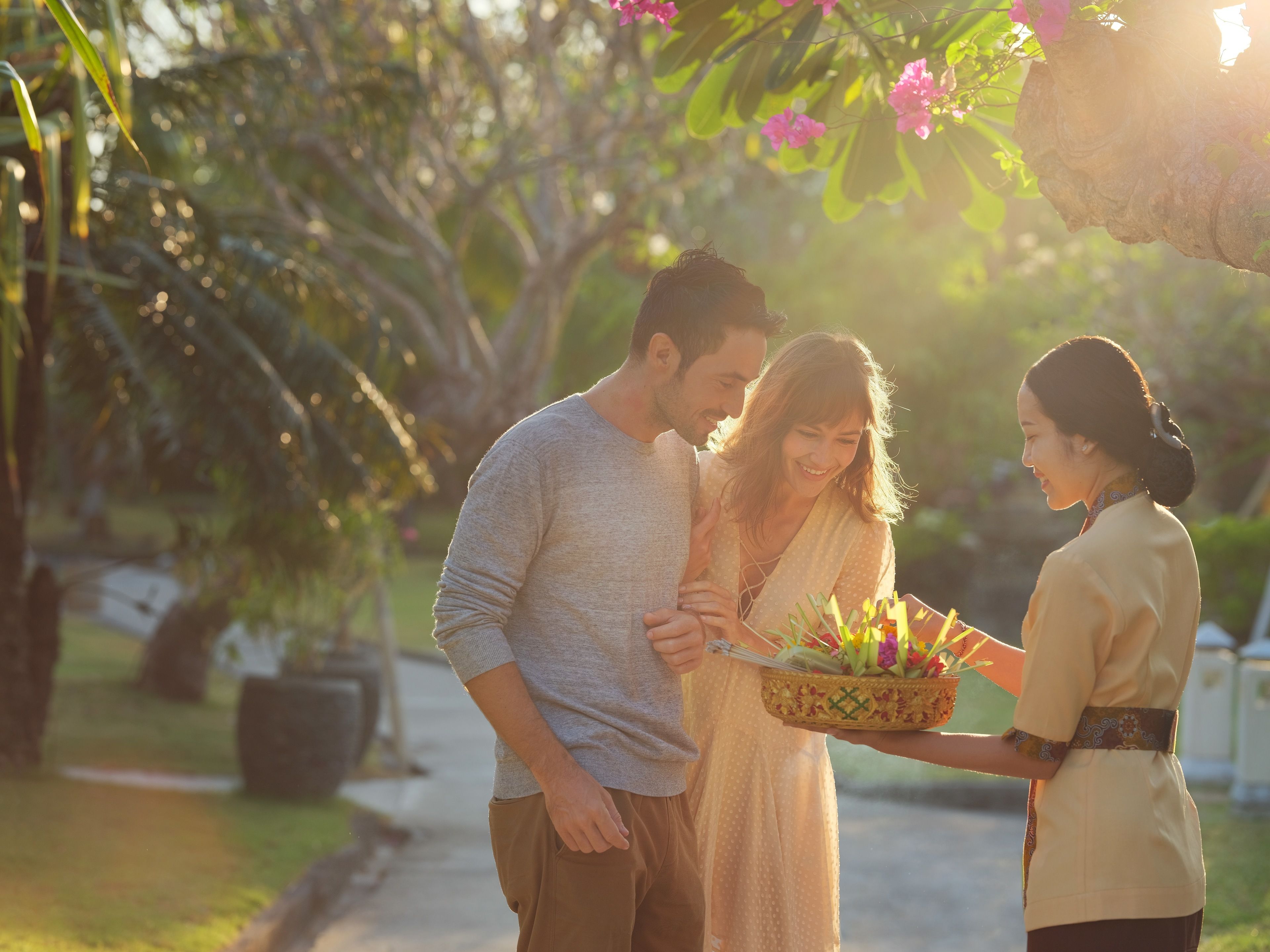 A couple embracing with a person holding a basket of flowers.