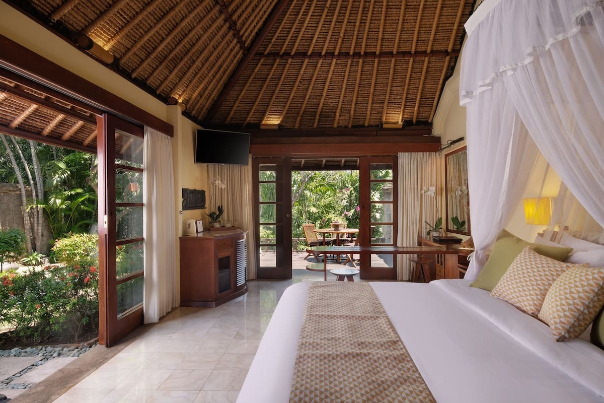 A spacious bedroom with a large bed, a TV, and a balcony with a dining area.