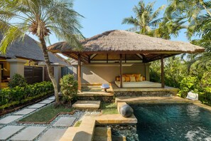 A thatched-roof outdoor seating area with a stone bench and a small pool. - Mimpi Resort Menjangan (Pejarakan)