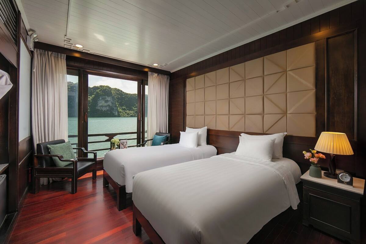 Habitación de hotel con dos camas, piso de madera, vista a un cuerpo de agua y una ventana con cortinas.