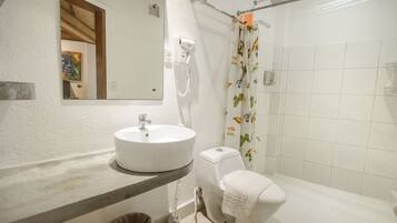 A bathroom with a white sink, toilet, and shower curtain with floral patterns.