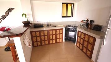 A kitchen with a stove, sink, and cabinets.