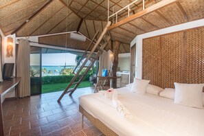 Quarto espaçoso com uma cama grande, uma escrivaninha e vista para o oceano.