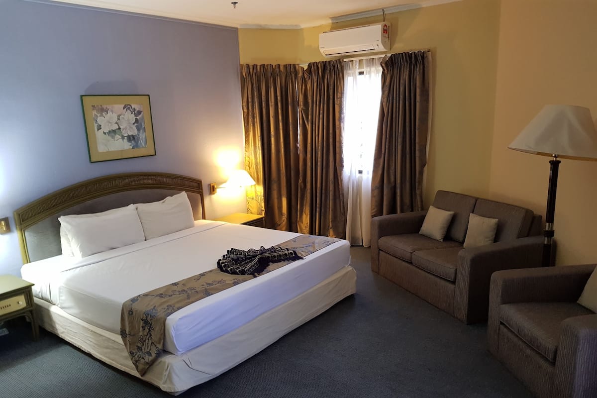 Ein Hotelzimmer mit einem großen Bett, einer Couch, einer Lampe und einer Klimaanlage.