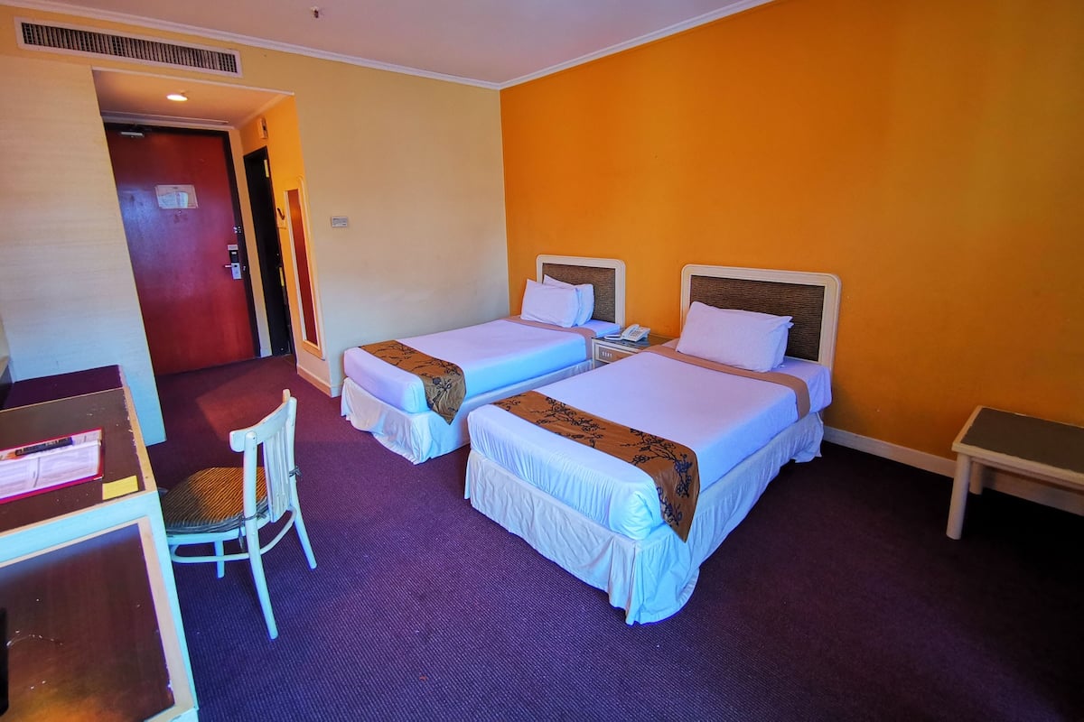 Ein Hotelzimmer mit zwei Betten, einem Schreibtisch, einem Stuhl und einem kleinen Tisch.