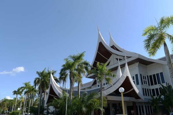 A traditional multi-tiered building with a curved roof and multiple balconies, surrounded by palm trees.