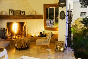A cozy living room with a fireplace, comfortable seating, and a dining area visible through a glass door. - Yalıçapkını Boutique Hotel - Boutique Class (Milas)