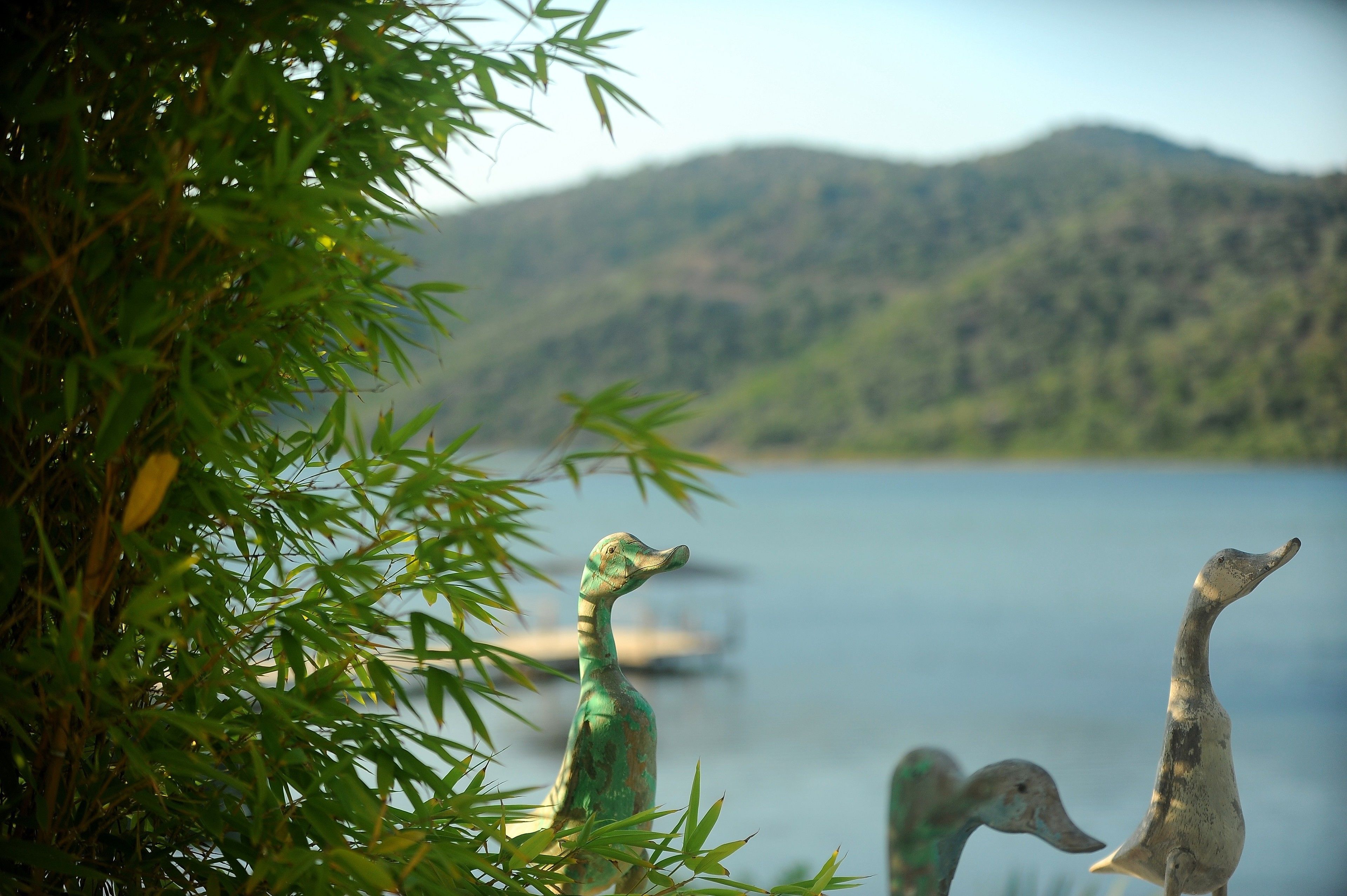 A serene lake with mountains in the background and two bird sculptures in the foreground.