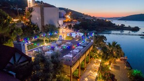 A rooftop terrace with outdoor seating, overlooking a body of water and a hilly landscape. - Yalıçapkını Boutique Hotel - Boutique Class (Milas)