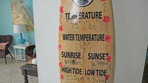 A wall with a weather forecast chart, including temperature and sunrise/sunset times. - Ocean Surf Inn & Suites (Huntington Beach)