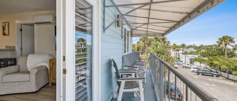 A balcony with a covered area, a sofa, and a dining table with chairs.