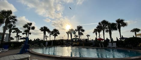 Una piscina al aire libre, sombrillas, sillones reclinables de piscina