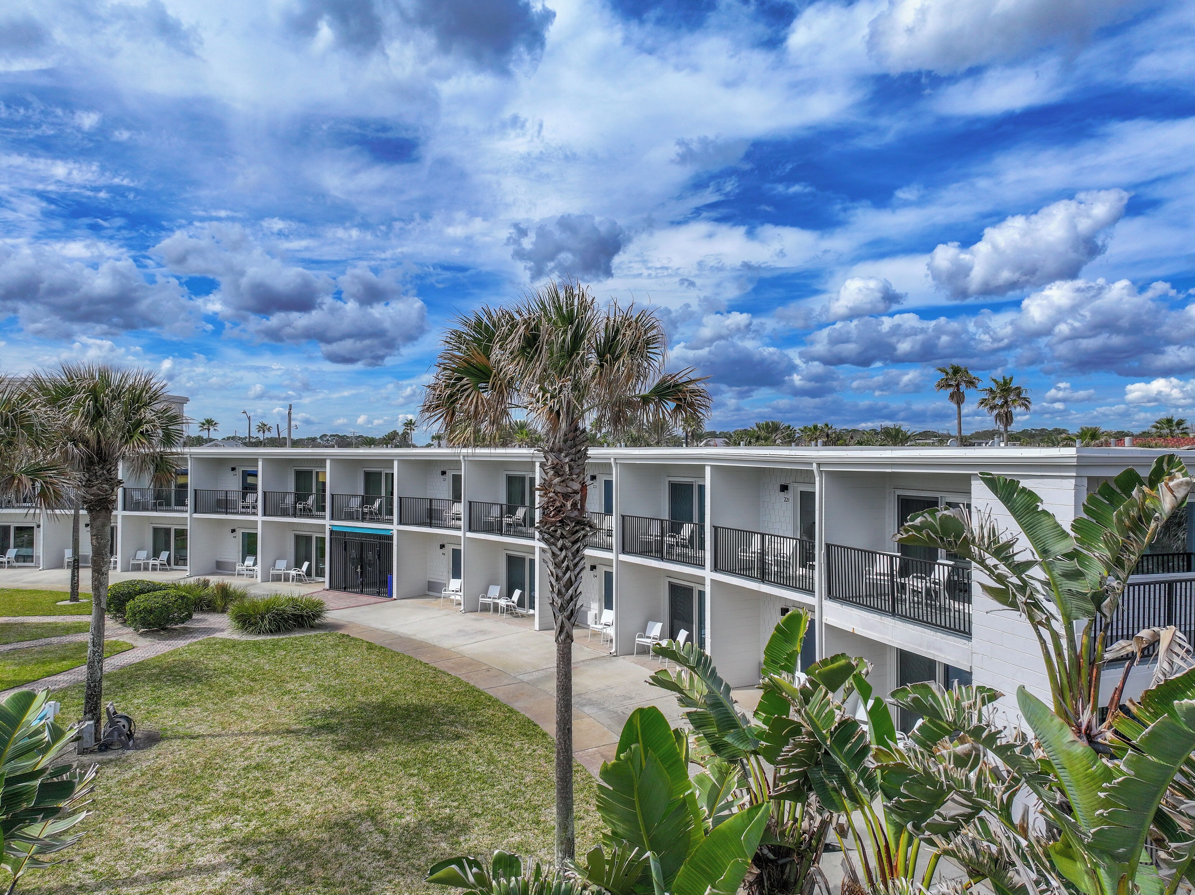 A multi-story hotel with balconies, a swimming pool, and tropical landscaping.