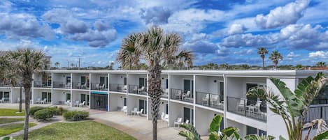 A multi-story hotel with balconies, a swimming pool, and tropical landscaping.