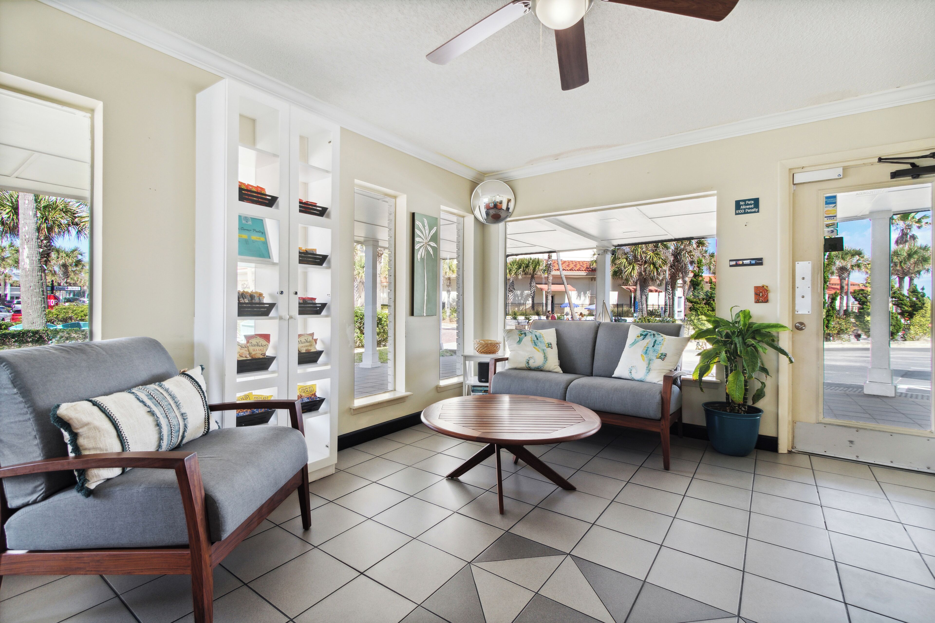 A hotel lobby with a seating area, a ceiling fan, and a view of the outside.
