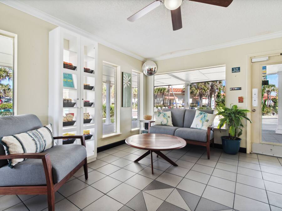 A hotel lobby with a seating area, a ceiling fan, and a view of the outside.