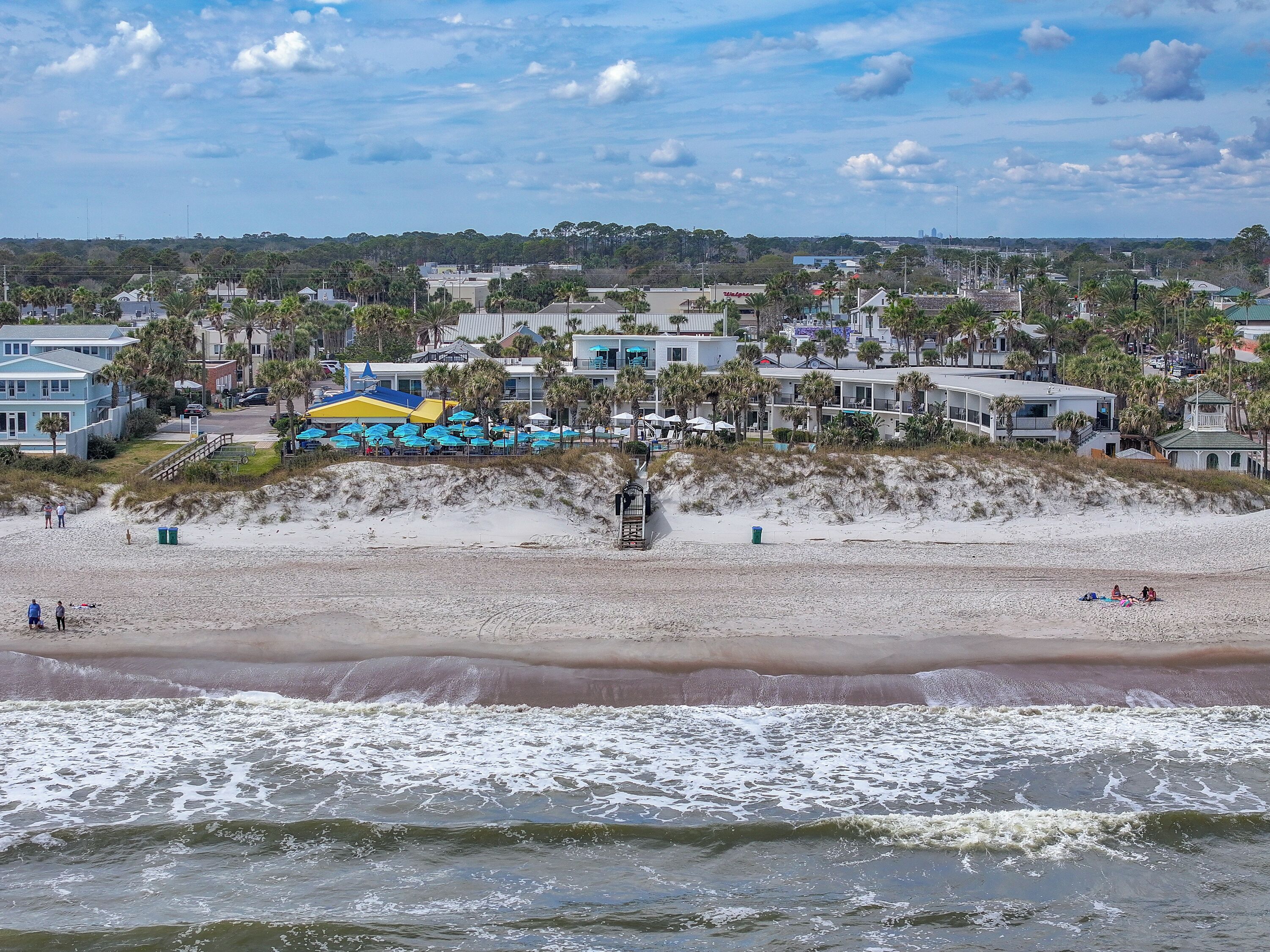 A beach with a row of beach umbrellas and a lifeguard tower.