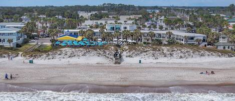 A beach with a row of beach umbrellas and a lifeguard tower.