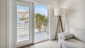 A room with a balcony, a sofa, and a floor lamp. - Seahorse Oceanfront Inn (Neptune Beach)