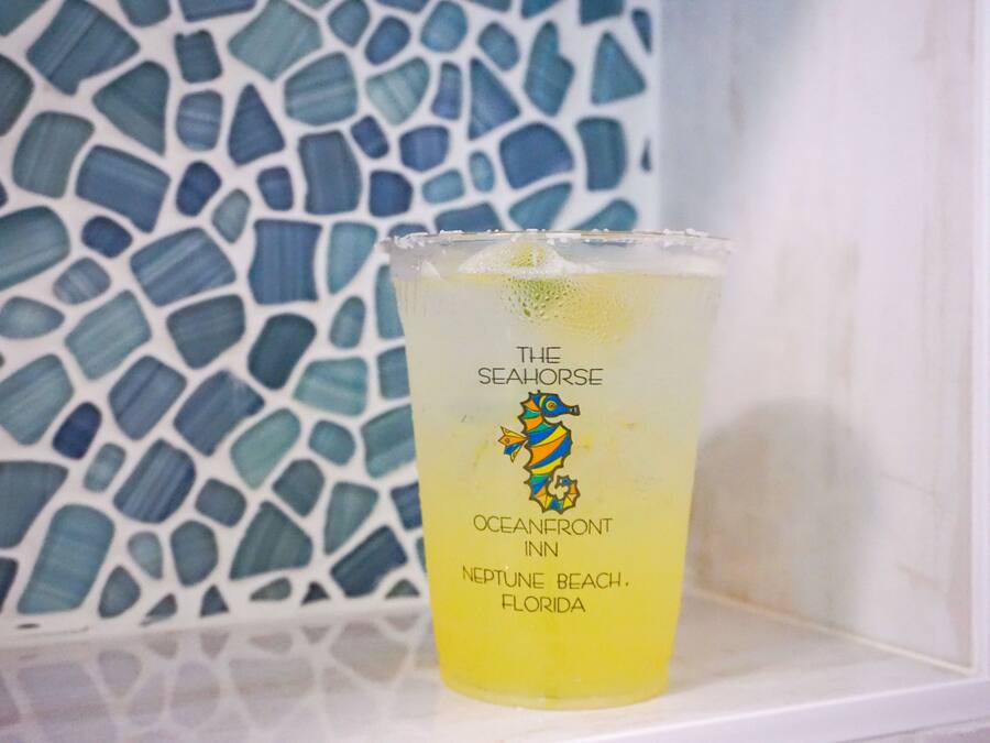 A glass with a label reading "The Seahorse" and "Oceanfront Inn, Neptune Beach, Florida" against a mosaic tile background.