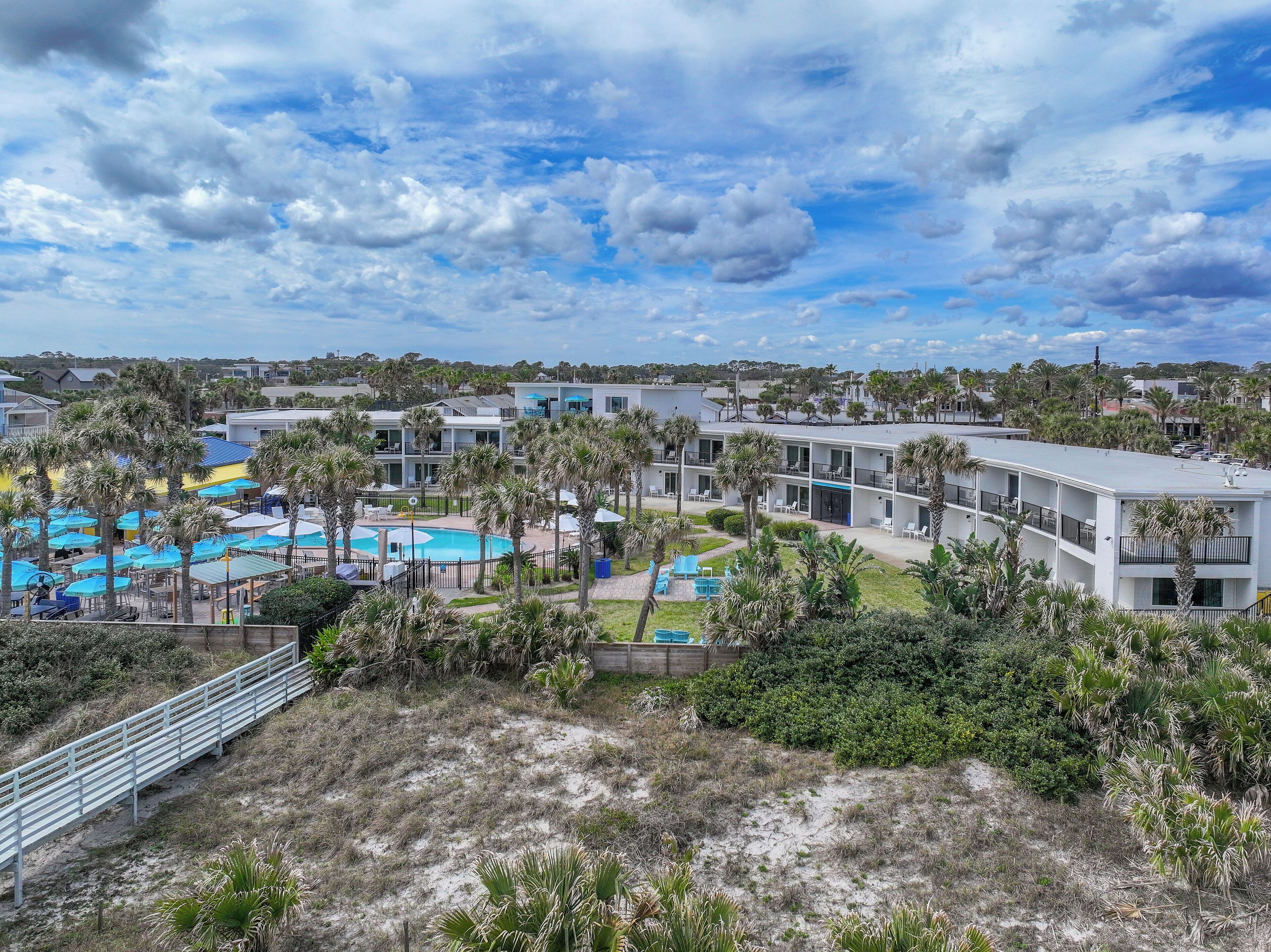 Un complejo turístico con varias edificaciones, piscina y palmeras.