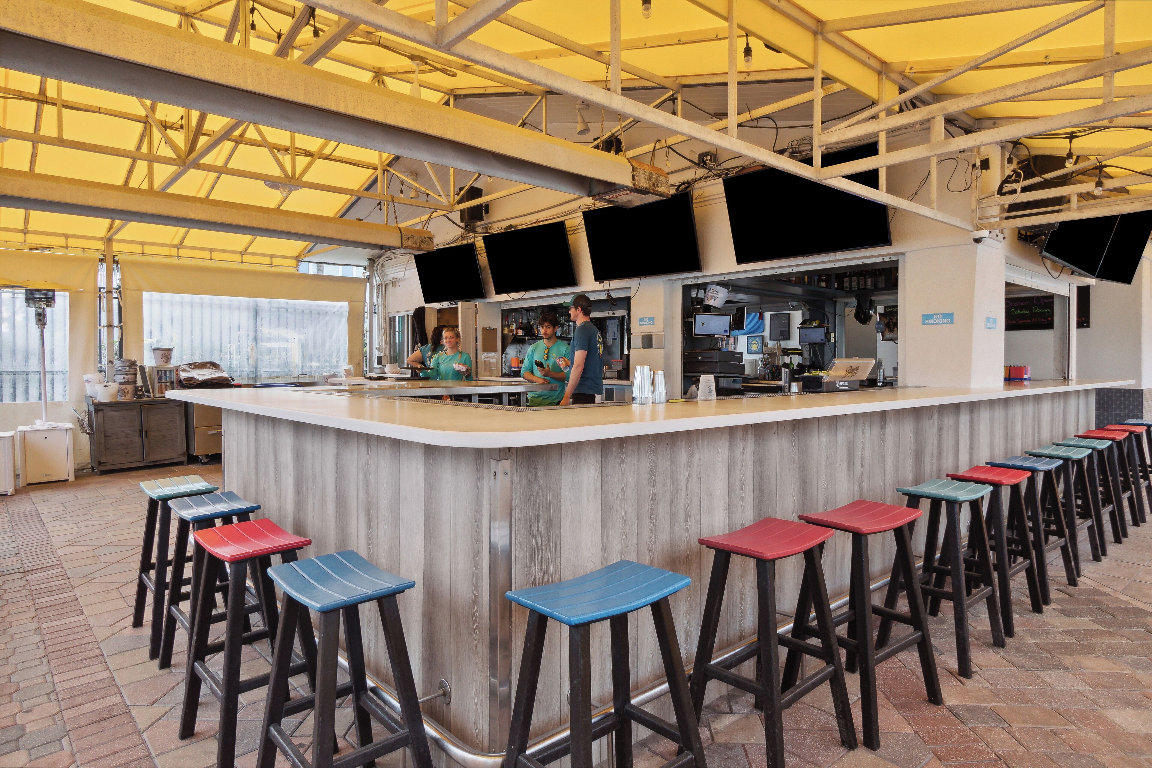 A bar area with stools, a counter, and a kitchen in the background.