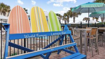 Relax in the outdoor seating area surrounded by palm trees, featuring a bench with a sign reading 'World Famous Lemon Bar'.