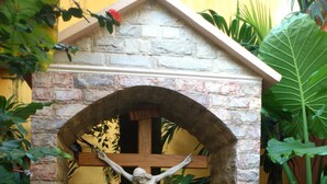 Una statua di Gesù Cristo sulla croce, circondata da vegetazione e una struttura in pietra.