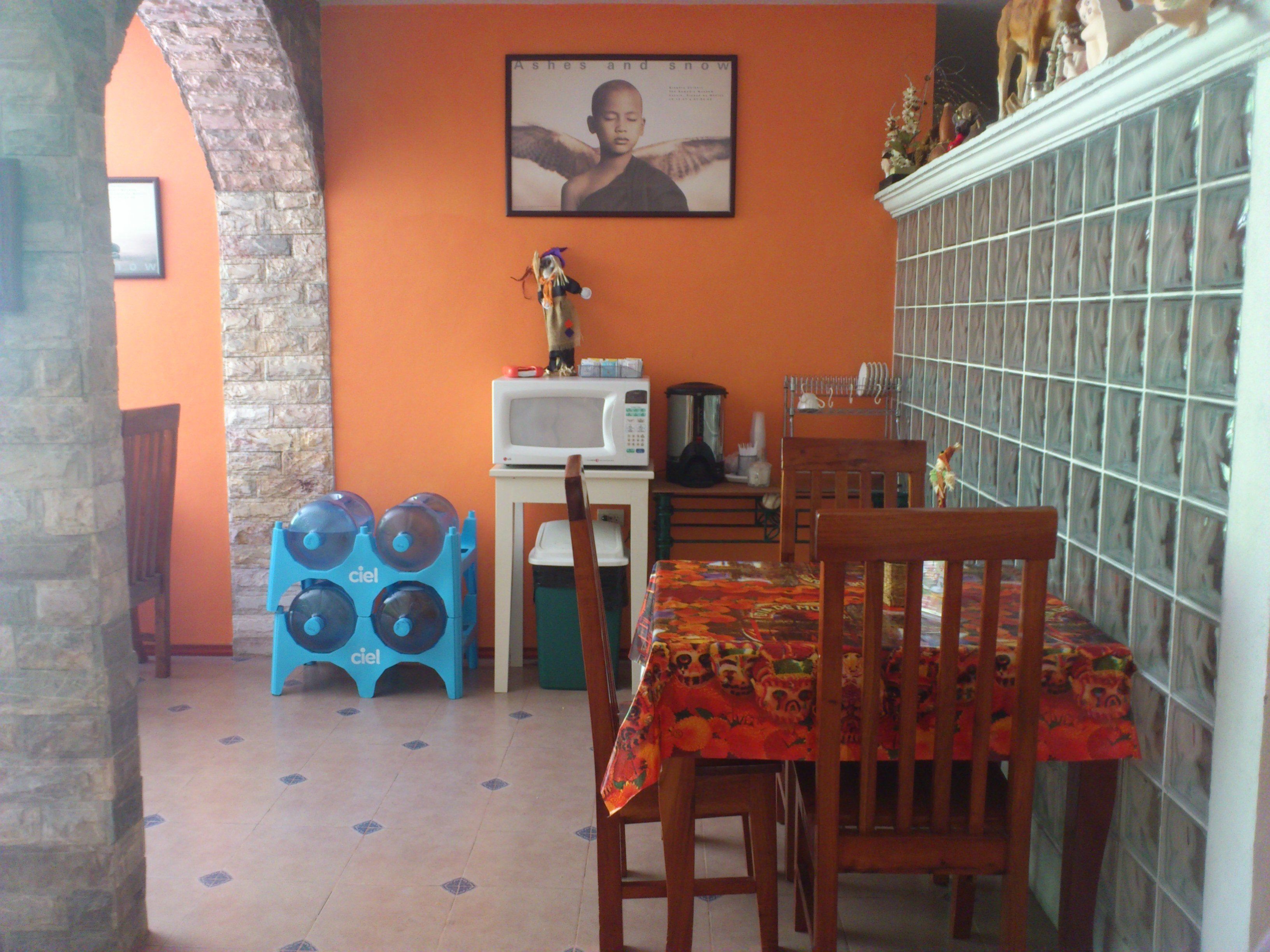 A dining area with a table set for two, a microwave, and a small kitchen area with a stove and sink.